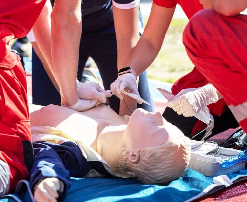 CPR being performed on a mannequin by students in red.