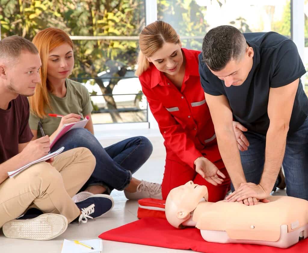 CPR being performed on mannequin by man in blue shirt. 